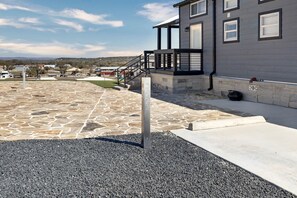 A building with a stone patio, a metal staircase, and a clear sky. - Charming and Modern Tiny Home Escape with Resort Amenities and Pool Near Fredericksburg, TX (Fredericksburg)