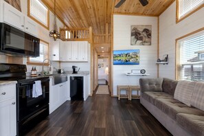 A compact kitchen with modern appliances, a dining area with a view, and a cozy seating area. - Charming and Modern Tiny Home Escape with Resort Amenities and Pool Near Fredericksburg, TX (Fredericksburg)