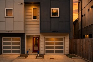 A two-story residential building with a garage entrance, a red door, and a small window on the upper floor. - NEW! Nashville Era Nights & Rooftop Dreams (Nashville)