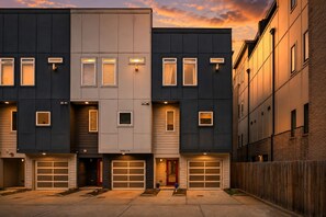 Un edifici residencial de diversos pisos amb entrada de garatge, un hidrant i una tanca de fusta.