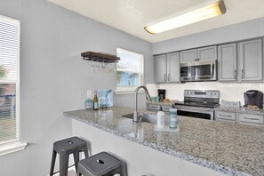 A kitchen with granite countertops, stainless steel appliances, and a coffee bar sign. - Canal-Front | Private Boat Slip | Minutes to Beach (Jamaica Beach)