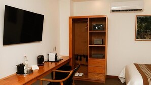 Una habitación de hotel con un escritorio de madera, televisor, armario y cama.
