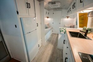 A compact kitchen with white cabinets, a built-in refrigerator, and a small countertop with a sink. - Glamping in an Airstream: Beautiful Accommodation near Tobermory, Canada (Northern Bruce Peninsula)