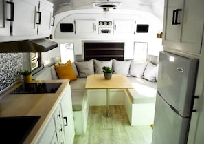 A compact RV interior with a kitchenette, seating area, and a refrigerator. - Glamping in an Airstream: Beautiful Accommodation near Tobermory, Canada (Northern Bruce Peninsula)