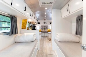 A compact RV interior with two sleeping areas, a kitchenette, and a dining area. - Glamping in an Airstream: Beautiful Accommodation near Tobermory, Canada (Northern Bruce Peninsula)