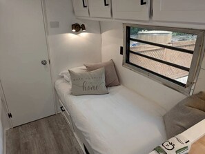 Un dormitorio compacto con una cama individual, una ventana con vistas y un armario pequeño.