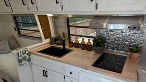 Uma cozinha compacta equipada com pia, fogão e armários.