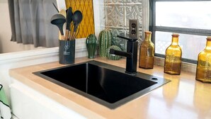 Uma cozinha com pia preta, cafeteira e objetos decorativos no balcão.