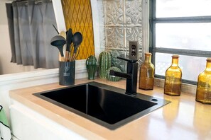 A kitchen with a black sink, a coffee machine, and decorative items on the counter. - Glamping in an Airstream: Beautiful Accommodation near Tobermory, Canada (Northern Bruce Peninsula)