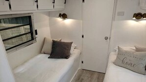 Quarto compacto com uma cama de solteiro, uma janela e uma porta.