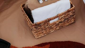A wicker basket with toiletries on a bed with a fox-patterned rug.