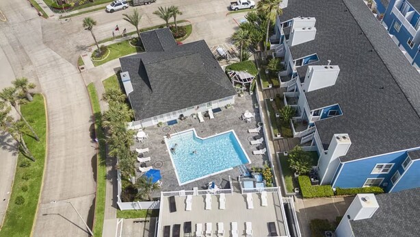 Vista aérea de um hotel com piscina, espreguiçadeiras e estacionamento.
