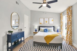 A bedroom with a bed, nightstands, a dresser, a ceiling fan, and artwork on the wall. - Pool + Free Parking | 2BR Galveston Hideout (Galveston)