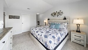 A bedroom with a bed, bedside tables, a dresser, and a wall-mounted artwork. - Palms Escape | Ocean View Condo | Pool | Pet-Friendly Retreat (Galveston)