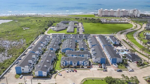 A coastal residential area with modern apartment buildings, a parking lot, and a beachfront hotel. - Palms Escape | Ocean View Condo | Pool | Pet-Friendly Retreat (Galveston)
