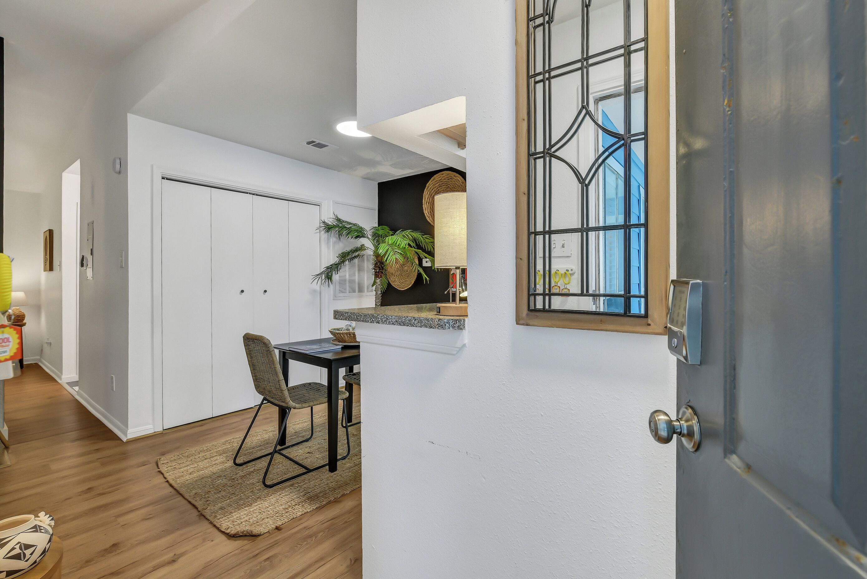 Eine moderne Küche mit weißen Schränken, eine Essecke mit Tisch und Stühlen sowie ein großes Fenster mit Blick.