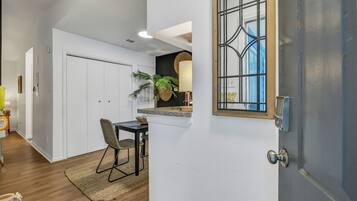 Eine moderne Küche mit weißen Schränken, eine Essecke mit Tisch und Stühlen sowie ein großes Fenster mit Blick.