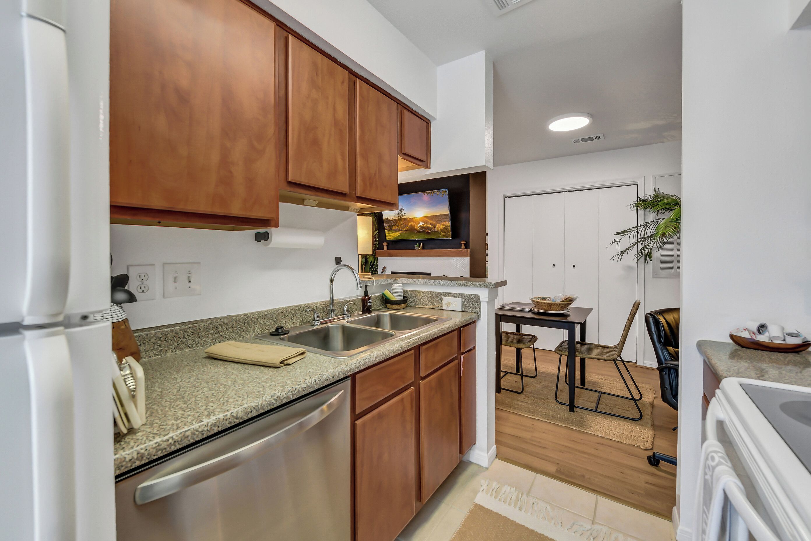 A modern kitchen with wooden cabinets, a granite countertop, and stainless steel appliances.