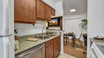 A modern kitchen with wooden cabinets, a granite countertop, and stainless steel appliances.