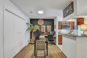 A compact kitchen with a microwave, stove, and wooden cabinets. - 2 Workspaces + Pool | Couples’ Galveston Escape (Galveston)