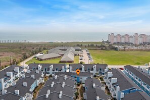 A coastal hotel with multiple-story buildings, a parking lot, and a view of the ocean. - The Salty Siren | Mermaid-Themed Condo | Pool Access | Private Patio (Galveston)