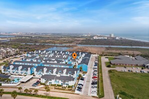A coastal hotel with multiple-story buildings, a parking lot, and a view of the beach and ocean. - The Salty Siren | Mermaid-Themed Condo | Pool Access | Private Patio (Galveston)