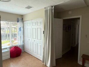 A room with a sliding door, a red bean bag chair, and a view through a window with blinds. - Deep Water Canal with 20' Floating Dock and Game Room (Crystal River)