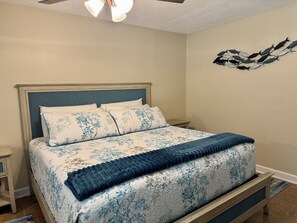 A bedroom with a bed, nightstands, a ceiling fan, and a wall art piece. - Deep Water Canal with 20' Floating Dock and Game Room (Crystal River)