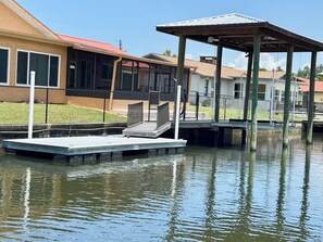 A waterfront property with a dock, a covered seating area, and a house with a red roof. - Deep Water Canal with 20' Floating Dock and Game Room (Crystal River)