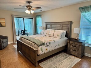 A bedroom with a wooden bed, a nightstand, a desk, and a ceiling fan. - Deep Water Canal with 20' Floating Dock and Game Room (Crystal River)