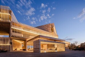 Un edificio moderno con un diseño arquitectónico único, que destaca por un techo inclinado y una serie de elementos verticales.