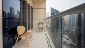 A balcony with a view of a cityscape, a chair, and a small table. - 1B Walk to Metro, Marina Mall with Skyline Views (Dubai)