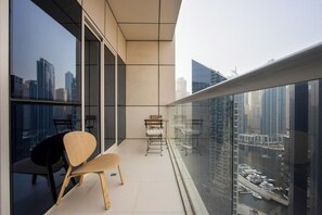 A balcony with a view of a cityscape, a chair, and a small table. - 1B Walk to Metro, Marina Mall with Skyline Views (Dubai)