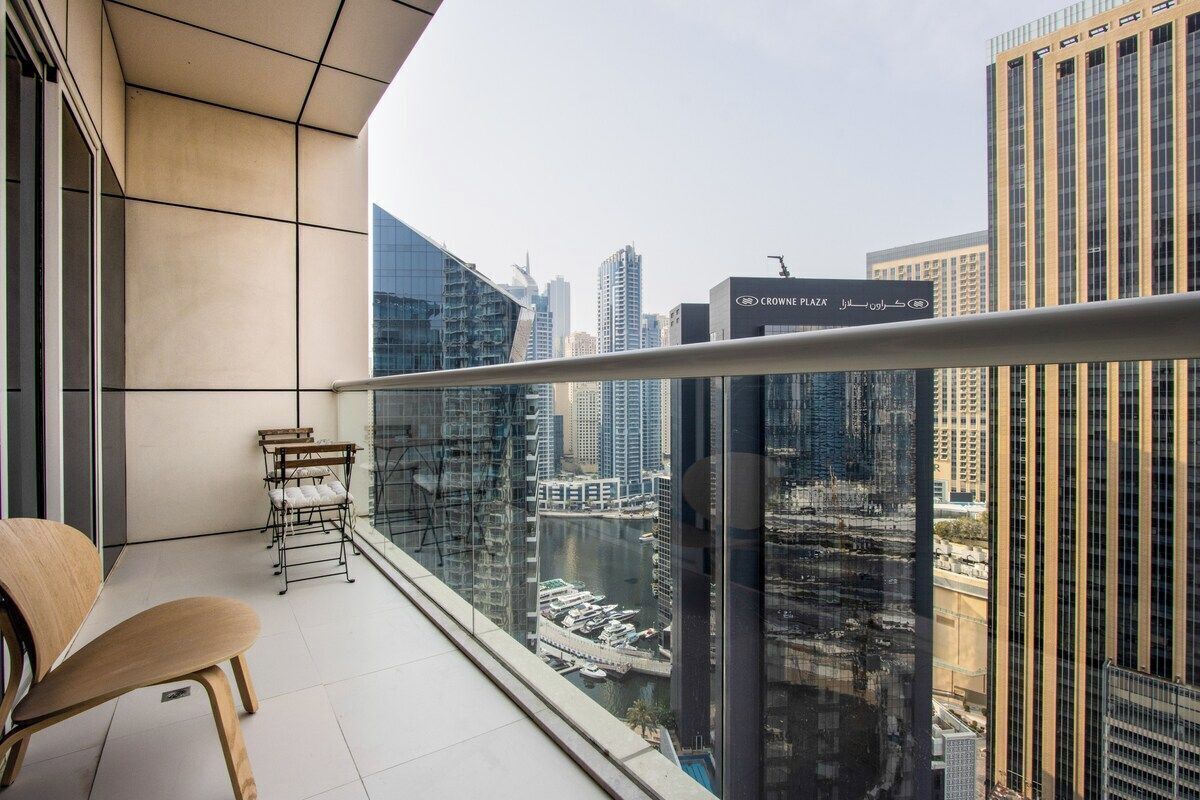 Un balcon offrant une vue sur le paysage urbain, avec notamment un port de plaisance et des immeubles de grande hauteur.