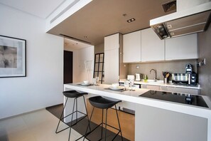 A modern kitchen with a central island, bar stools, and a coffee machine. - 1B Walk to Metro, Marina Mall with Skyline Views (Dubai)
