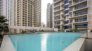 A swimming pool with lounge chairs, surrounded by high-rise buildings. - 1B Walk to Metro, Marina Mall with Skyline Views (Dubai)