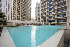 A swimming pool with lounge chairs, surrounded by high-rise buildings. - 1B Walk to Metro, Marina Mall with Skyline Views (Dubai)