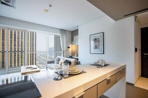 Ein modernes Hotelzimmer mit großem Fenster, Essecke und einer Küchenzeile.