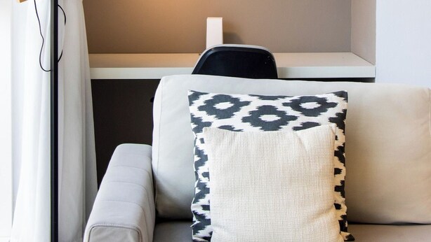 A modern living room with a sofa, a lamp, a framed artwork, and a vase on a shelf. - 1B Walk to Metro, Marina Mall with Skyline Views (Dubai)