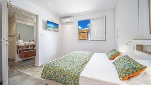 Een slaapkamer met een bed, nachtkastje, spiegel en een raam met uitzicht.