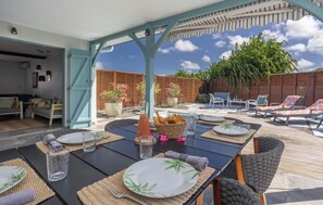 An outdoor dining area with tables set for two, surrounded by lounge chairs and a covered seating area. - 2 Villas with 2 Private Pools - Luxury and Nature in Martinique (Sainte-Luce)