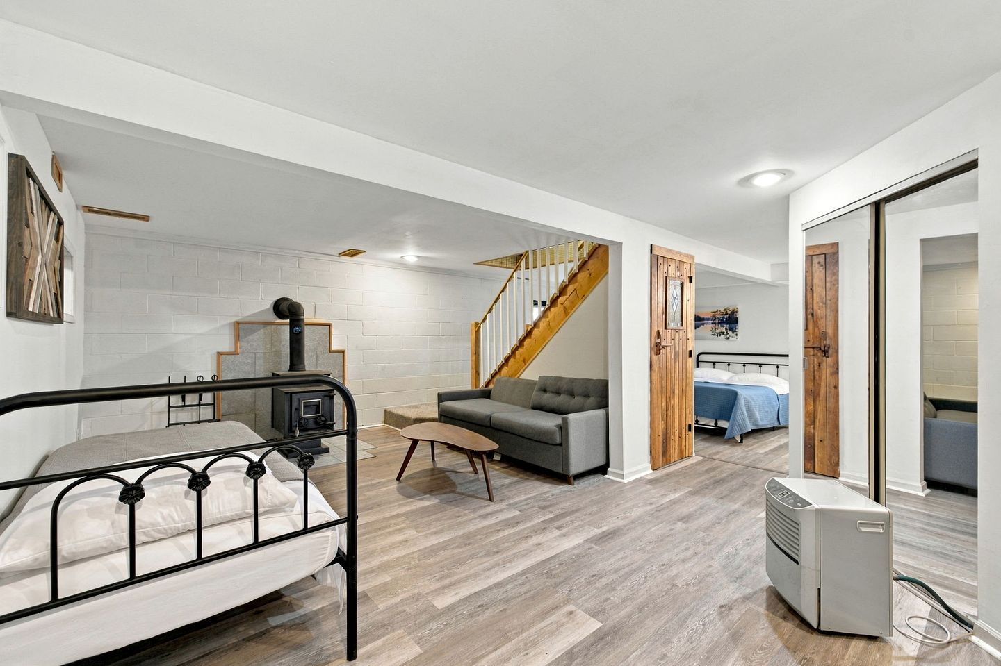 Un salon moderne comprenant un lit, un canapé, un escalier et une chambre à coucher séparée, également dotée d’un lit.