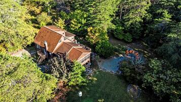 A two-story house with a large deck and a small pond.