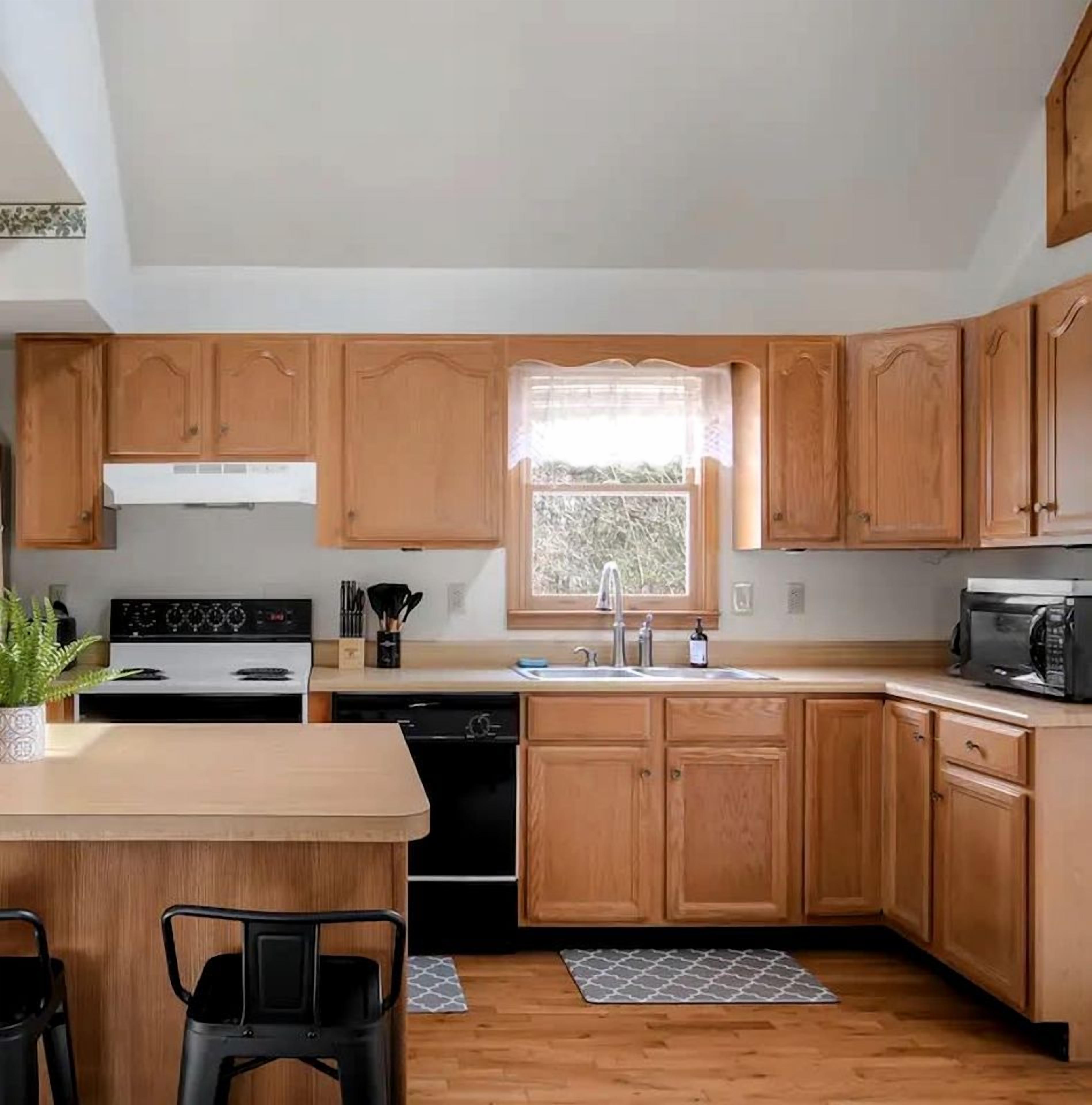 A kitchen with wooden cabinets, a stove, a sink, and a window.