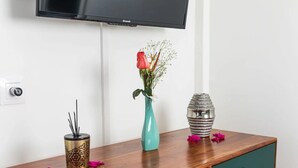 Eine Holzkommode mit einem türkisfarbenen Krug, der eine einzelne Rose und ein dekoratives Metallstück enthält.