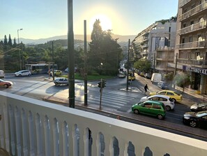 A busy urban street scene with vehicles, a pedestrian crossing, and buildings. - Acropolis Oasis | Designer Home by the Acropolis (Athina)