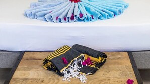 Una cama bien hecha con un arreglo de toallas y un cojín decorativo.