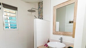 Un baño con ducha, lavamanos y espejo.