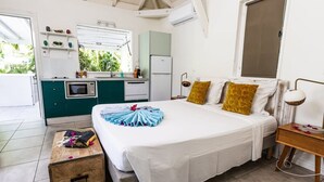 Habitación de hotel con una cama, mesita de noche y vista a la cocina.