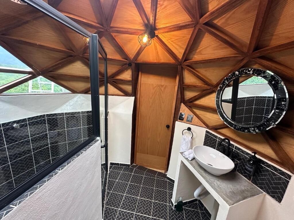 A bathroom with a wooden ceiling, a large mirror, and a sink.